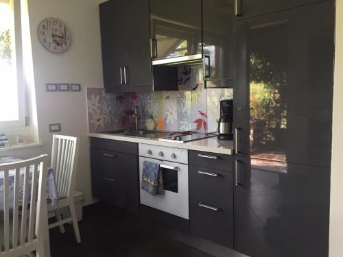 a kitchen with black cabinets and a white stove top oven at Trento Small View in Trento