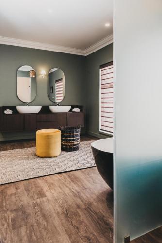 a bathroom with two sinks and a tub and mirrors at The Feather Hill Boutique Hotel in Potchefstroom