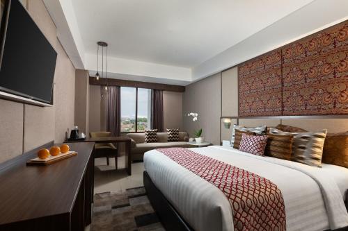 a hotel room with a large bed and a desk at The Alana Hotel & Conference Center Malioboro Yogyakarta by ASTON in Yogyakarta