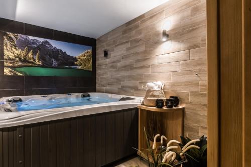 a bathroom with a jacuzzi tub with a picture on the wall at Villa Kaplowa Chata & SPA in Zakopane