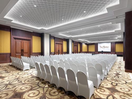 a conference room with white chairs and a podium at The Alana Hotel & Conference Center Malioboro Yogyakarta by ASTON in Yogyakarta