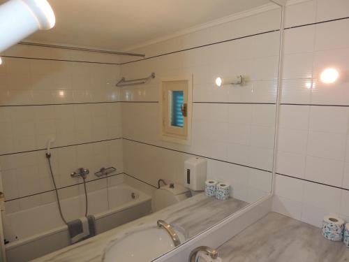a bathroom with a bath tub and a sink at Surfing Beach Village Paros in Santa Maria