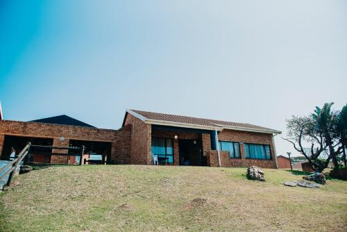 a brick house on top of a grassy hill at Port Edward Holiday Resort in Port Edward