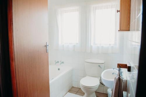 a bathroom with a toilet and a tub and a sink at Port Edward Holiday Resort in Port Edward