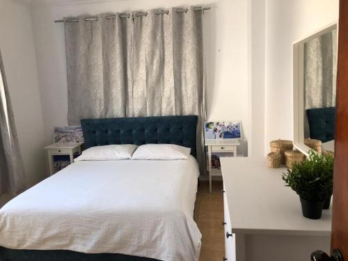 Schlafzimmer mit einem Bett mit blauem Kopfteil in der Unterkunft Jolie appartement vue mer in Mʼdik