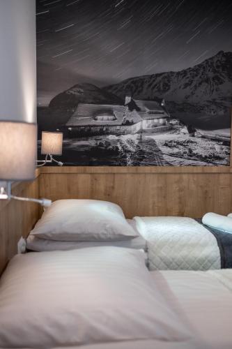 a bedroom with two beds and a painting on the wall at Pokoje u Nasyj Kasi in Poronin