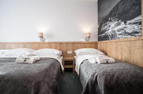 two beds in a hotel room with white pillows at Pokoje u Nasyj Kasi in Poronin
