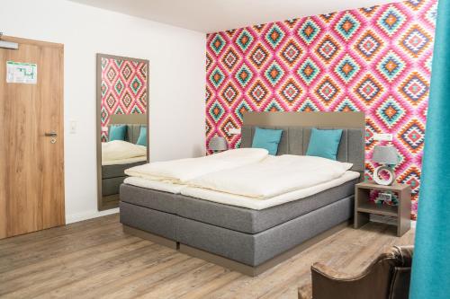 LangfördenにあるHotel Am Domのベッドとカラフルな壁のある寝室