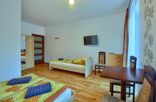 a living room with a bed and a table and a room at Centrum Noclegi in Krynica Zdrój