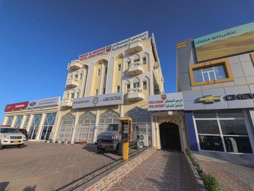 Super OYO 108 Marsa Al Masafar Hotel Apartment في صور: مبنى كبير فيه سيارة متوقفة أمامه