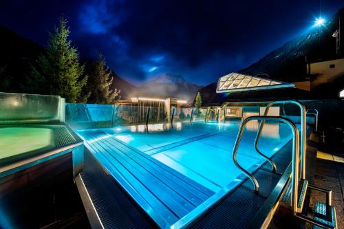 una piscina por la noche con las luces encendidas en MANNI das Hotel, en Mayrhofen