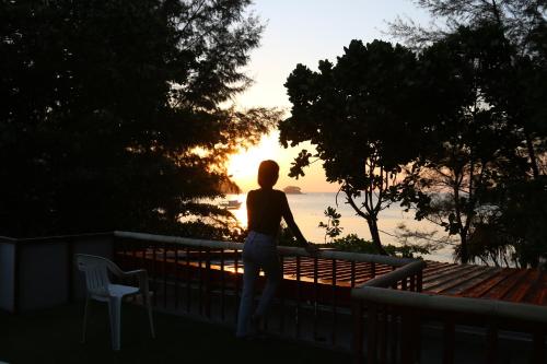 a woman standing on a balcony looking at the water at Ruan Mai Naiyang Beach Resort - SHA Plus in Nai Yang Beach