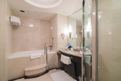a bathroom with a tub and a sink and a shower at JR Hotel Clement Takamatsu in Takamatsu