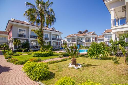 a row of houses with palm trees in a yard at Legend Apartments in Fethiye