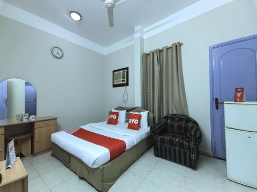 Habitación de hotel con cama y silla en Super OYO 108 Marsa Al Masafar Hotel Apartment, en Sur