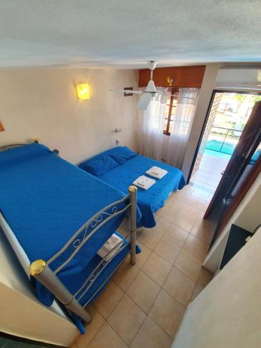 um quarto com uma cama com lençóis azuis e uma janela em Hotel Carlos Paz em Villa Carlos Paz