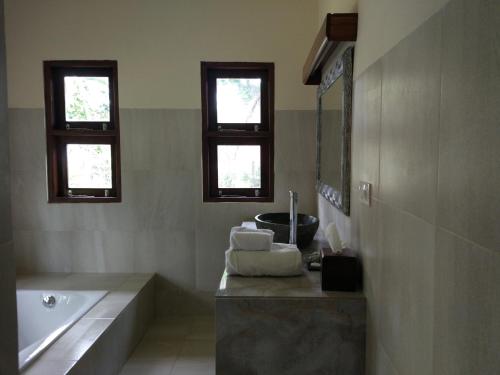 Selemadeg的住宿－伽亞米娜海灘度假酒店，带浴缸和水槽的浴室以及2扇窗户。