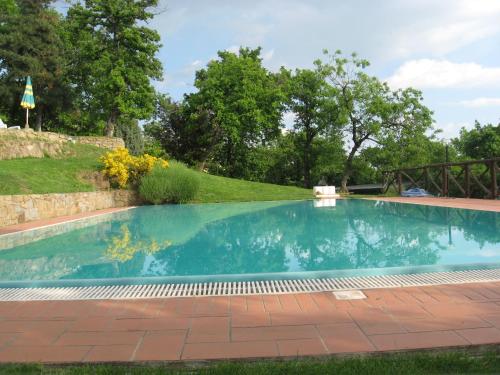 a swimming pool in a yard with a stone wall and trees at Agriturismo La Capitata in Pian di Scò