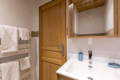 a bathroom with a sink and a wooden cabinet at Résidence La Forêt du Praz - Courchevel 1850 in Courchevel