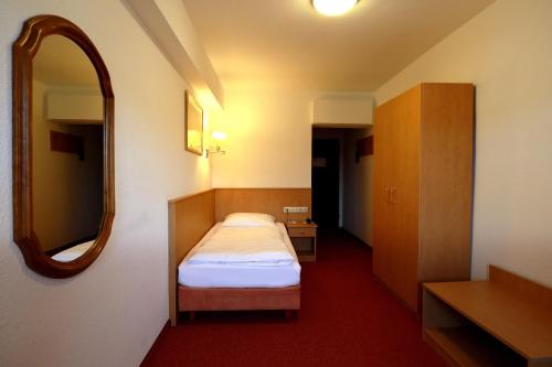 a hotel room with a bed and a mirror at Mariaweiler Hof in Düren - Eifel
