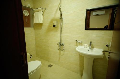 a bathroom with a sink and a toilet and a shower at Alpha Suites Hotel in Salalah