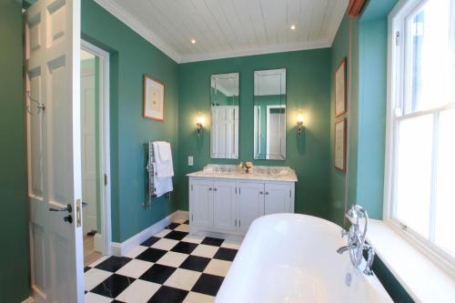 a bathroom with green walls and a sink and a tub at La Cotte The Manor House in Franschhoek