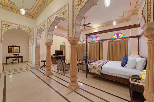a bedroom with a bed and a desk in a room at The Jai Bagh Palace in Jaipur