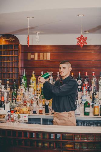 a man standing behind a bar with a drink at Hotel Miletto in San Massimo