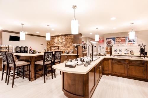 a large kitchen with wooden cabinets and bar stools at Staybridge Suites - Fort Lauderdale Airport - West by IHG in Davie