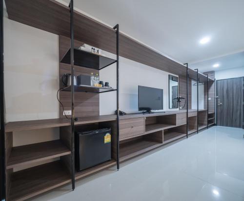 a living room with wooden shelves and a television at Tassana Place in Chon Buri