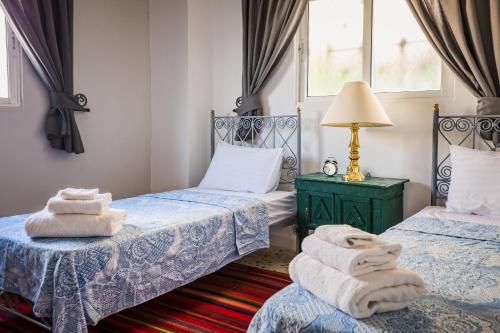 two beds in a room with towels on the floor at Beit Al Baraka in Um Qeis