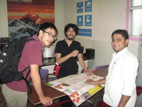 three men standing around a table with a map at Smyle Inn - Best Value Hotel near New Delhi Station in New Delhi