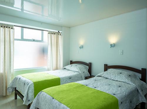 1 dormitorio con 2 camas y ventana en ApartaHotel Luxury, en Paipa