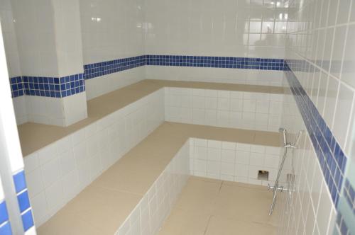 a bathroom with a tub with blue and white tiles at Havana Palace Hotel II in Uberaba