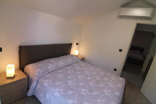 a small bedroom with a bed and two lamps at SeaHouse 114 in Mali Lošinj