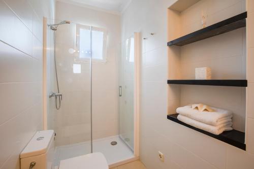 y baño blanco con ducha y aseo. en Villa Mumare, en Cala d´Or