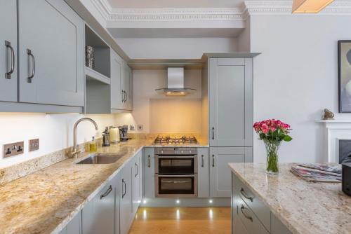 a kitchen with white cabinets and a vase of flowers at Brunswick Place in Bath