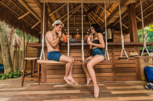 a man and a woman sitting on a bench at Hotel Carolina Bacalar in Bacalar