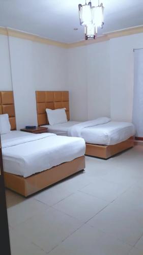 two beds in a room with white walls at القبة الذهبية للشقق المخدومة in Riyadh