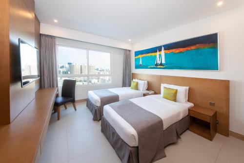 a hotel room with two beds and a window at Ramada by Wyndham Beach Hotel Ajman in Ajman 