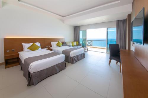 two beds in a hotel room with a view of the ocean at Ramada by Wyndham Beach Hotel Ajman in Ajman 