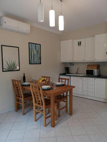 a kitchen with a wooden table and chairs in it at Kiss - Apartamentos in Albufeira