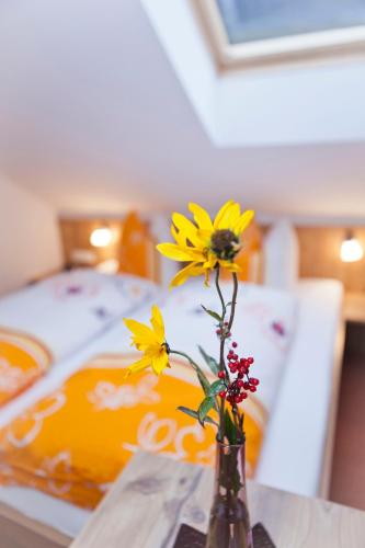a vase with flowers on a table with a bed at Alpenapart Marina in Nauders