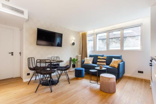 a living room with a blue couch and a table at CMG Résidence Canal Saint-Martin Vellefaux in Paris