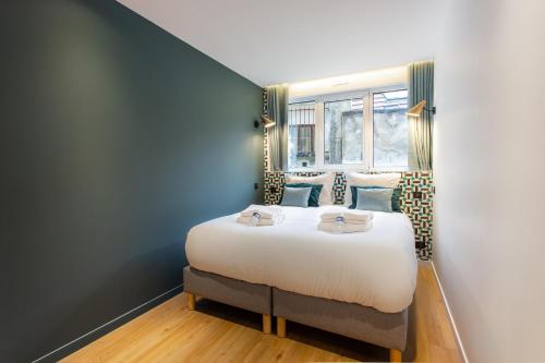 a bedroom with a large bed with a window at CMG Résidence Canal Saint-Martin Vellefaux in Paris