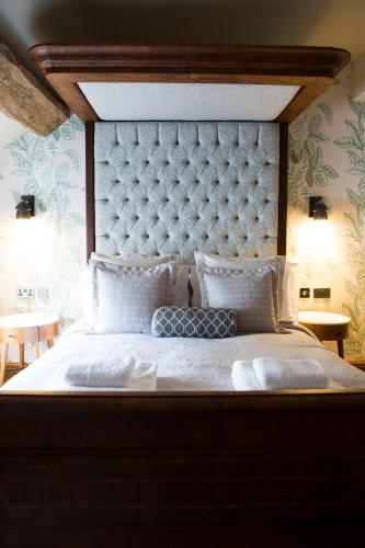 a bedroom with a large bed with a large headboard at The Legh Arms Prestbury in Macclesfield