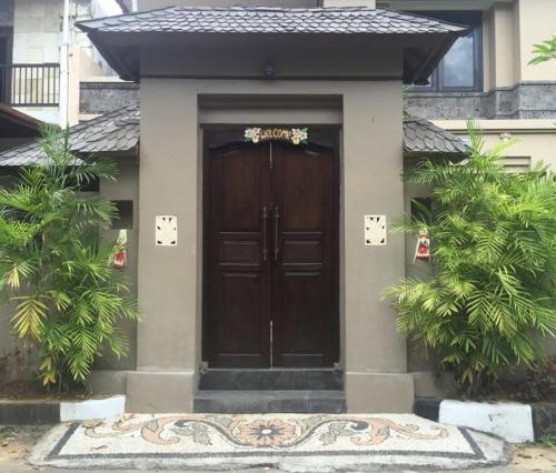 a house with a wooden door in front of it at Villa Indah Kuta Royal - Private Pool - Optic Fiber High Speed Internet in Kuta
