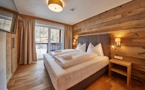 a bedroom with a large bed with a wooden wall at Residenz Der Wieshofer in Saalbach-Hinterglemm