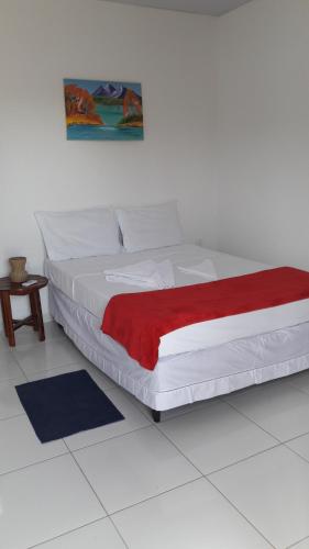 a white bed with a red blanket on top of it at Villa Portal dos Ventos in Fortim
