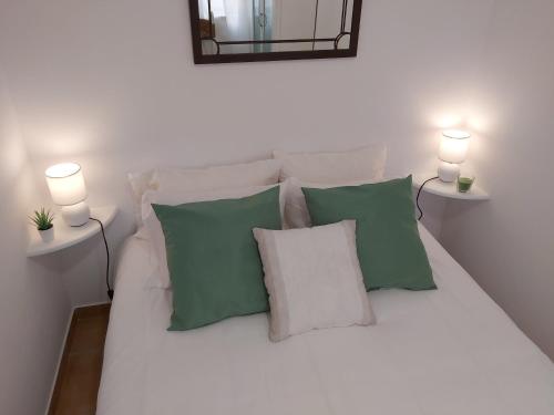 a white bed with green and white pillows and two lights at Sun and Beach II AC Wifi 90mts from the Beach in Portimão
